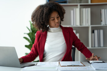 African american businesswoman working with laptop looking at financial information Successful business results in modern office with happy note taking in folder.