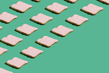 Creative idea toasted bread with pink spread like a pattern. Minimal concept toast for breakfast on pastel green background.