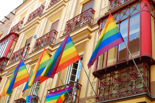 Many LGBT gay flags hanging and waving on the festive vintage building in the centre of Madrid, Spain. Horizontal photo of equality symbol on gay pride day