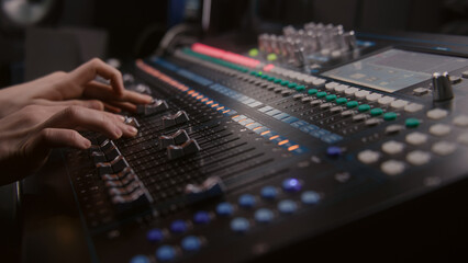 Audio engineer uses mixing console, remote control for adjusting sound, audio mixer. Musician...