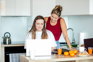 Female employees work at home, in kitchen on joint project, there is freshly squeezed orange juice nearby. Comfort.