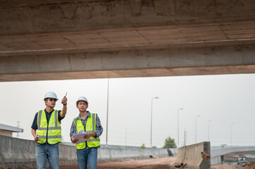 Asian male highway engineering working with architects talking and blank sheet good teamwork Engineer working on motorway bridge and concrete road at construction site