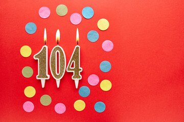 Number 104 on a red background with colored confetti. Happy birthday candles. The concept of...