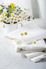 Fototapeta na wymiar wild daisy flowers and white linen tablecloth