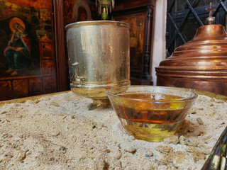 Wishing  candle in a glass on an iron table in an old orthodox chapel with religious icons