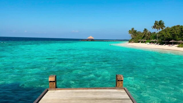 A wooden jetty ends at the turquoise sea of the Maldives