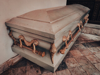 close up shot of a metal casket with gold ornaments in a chapel or funeral home before funeral or burial at cemetery - obrazy, fototapety, plakaty
