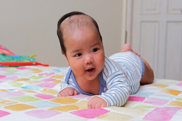 Asian infant showing happy face expression when doing tummy time