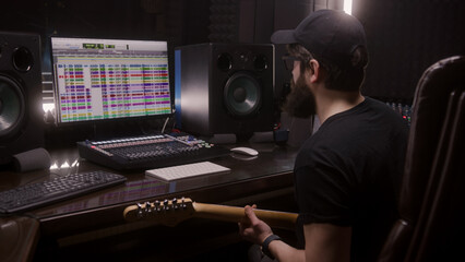 Sound engineer, musician plays electric guitar, records melody for creating new song. Computer...