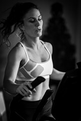 Fototapeta na wymiar Woman exercising on cycling machine or exercise bike, black and white