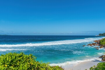 Tropical scenery with a sandy beach and turquoise ocean on La Digue island in Seychelles.
