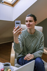 middle-aged woman, in a sweater, does sitting in a chair, at home. Communication via video call