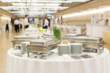 Waiters prepare buffet before a coffee break at business conference meeting. Focus on plates and dishes on the table.