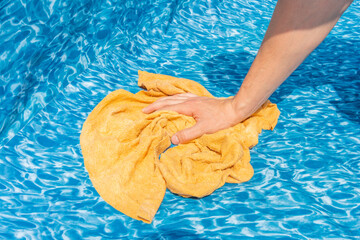 Cose-up on a hand with a rag when cleaning a garden pool. Preparation for the summer season.