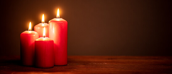 four red candles against dark background with copy space  for banner, panorama or border with copy...