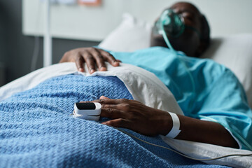 African American senior man with oxygen mask lying on bed in hospital ward - Powered by Adobe