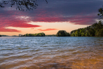 Naklejka na ściany i meble a gorgeous spring landscape at Lanier Point Park with rippling blue water surrounded by lush green trees and plants with powerful cloud at sunset at Lake Lanier in Gainesville Georgia USA