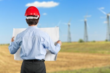 Young engineer or technician stand on windmill field background