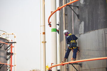 Male worker down height tank roof rope access safety inspection of thickness storage tank