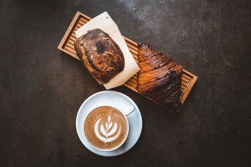 sourdough bun with cheese and a croissant and a coffee with latte art 
