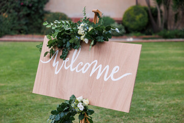 cartello in legno che indica la scritta "welcome" e intorno una fantastica decorazione floreale