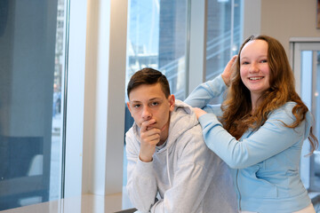 Fototapeta premium Cheerful young couple two friends in pastel blue casual clothes, woman hugging man, standing behind him, looking High quality photo