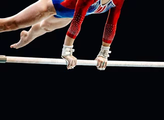 Deurstickers close-up female gymnast exercise on uneven bars in artistic gymnastics, black background, sports summer games © sports photos