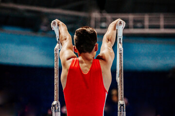 rear view athlete gymnast begin exercise parallel bars in championship gymnastics artistic