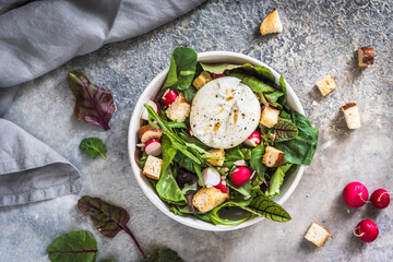 Mixed salad with radishes, homemade croutons and burrata cheese on gray background, top view - obrazy, fototapety, plakaty