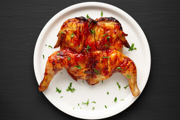 Homemade Spatchcocked Grilled Piri-Piri Chicken with Parsley on a Plate, top view. Overhead, from above, flat lay. Close-up.