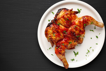 Homemade Spatchcocked Grilled Piri-Piri Chicken with Parsley on a Plate, top view. Overhead, from above, flat lay. Copy space.