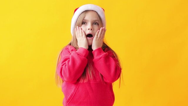 portrait of a little girl in a santa hat on a yellow background