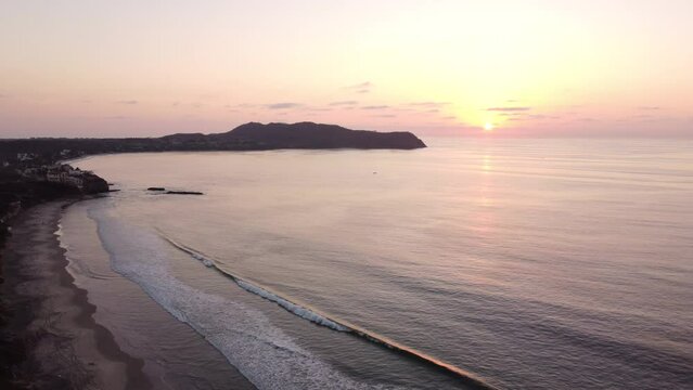 Drone view over sea waves covering a sandy coastline during sunset in Punta Mita