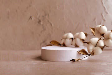 white round podium with branch of cotton on beige natural background. Mockup to promote eco or organic product , cosmetics.