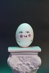 Animated egg with drawings of different faces and expressions mounted on a column in a large photograph
