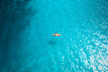 Photo en drone d'une femme sexy sur un paddle dans une eau bleu turquoise