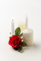 Fototapeta na wymiar burning candle with other candles and red rose on the white background lamp steel flame fire