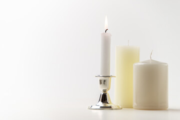 burning candle with other candles on a white background metallic lamp steel flame fire