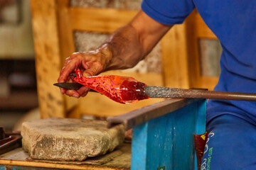 Murano glass blower holds a red hot glass horse sculpture