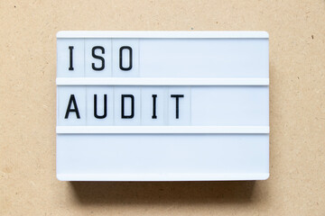 Lightbox with word ISO audit on wood background