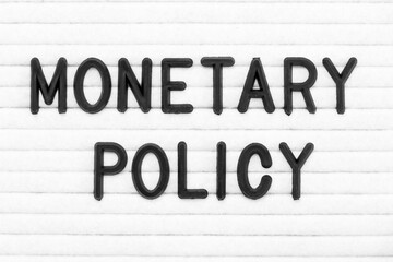 Black color letter in word monetary policy on white felt board background