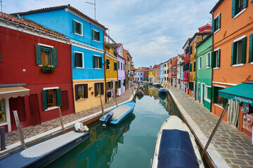 Colorful architecture and canal with boats in Burano island, Venice, Italy. Famous travel destination.