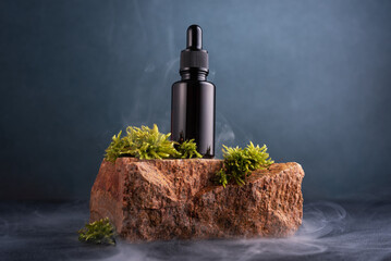 Glass bottle of cosmetic product on the stone with moss