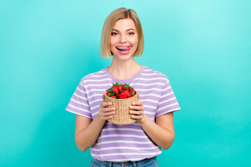 Photo of satisfied woman bob hairdo dressed striped t-shirt hold basket of strawberries tongue lick lips isolated on teal color background