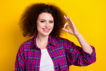 Photo of optimistic young good mood lady wear stylish plaid violet plaid shirt show okey symbol new product sale isolated on yellow color background