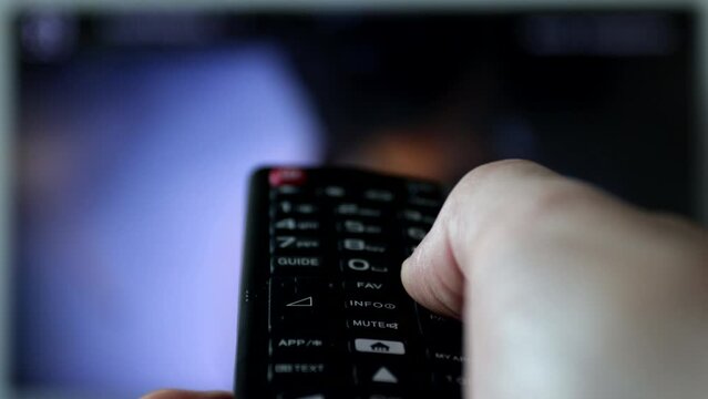 Close-up of a remote control held by a man while changing channels.