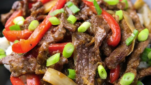 Stir fry Crispy Orange Beef with sweet peppers, onion and rice. Rotating video