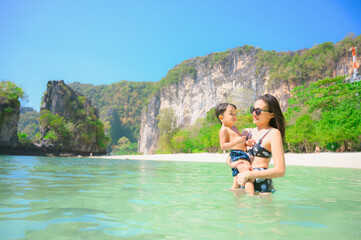 Fototapeta na wymiar Happy mother and son resting at beach in summer, Krabi, Thailand
