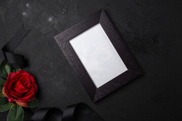 top view black bow with red flower and picture frame on a dark surface funeral death