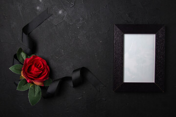 top view black bow with red flower and picture frame on dark surface funeral death